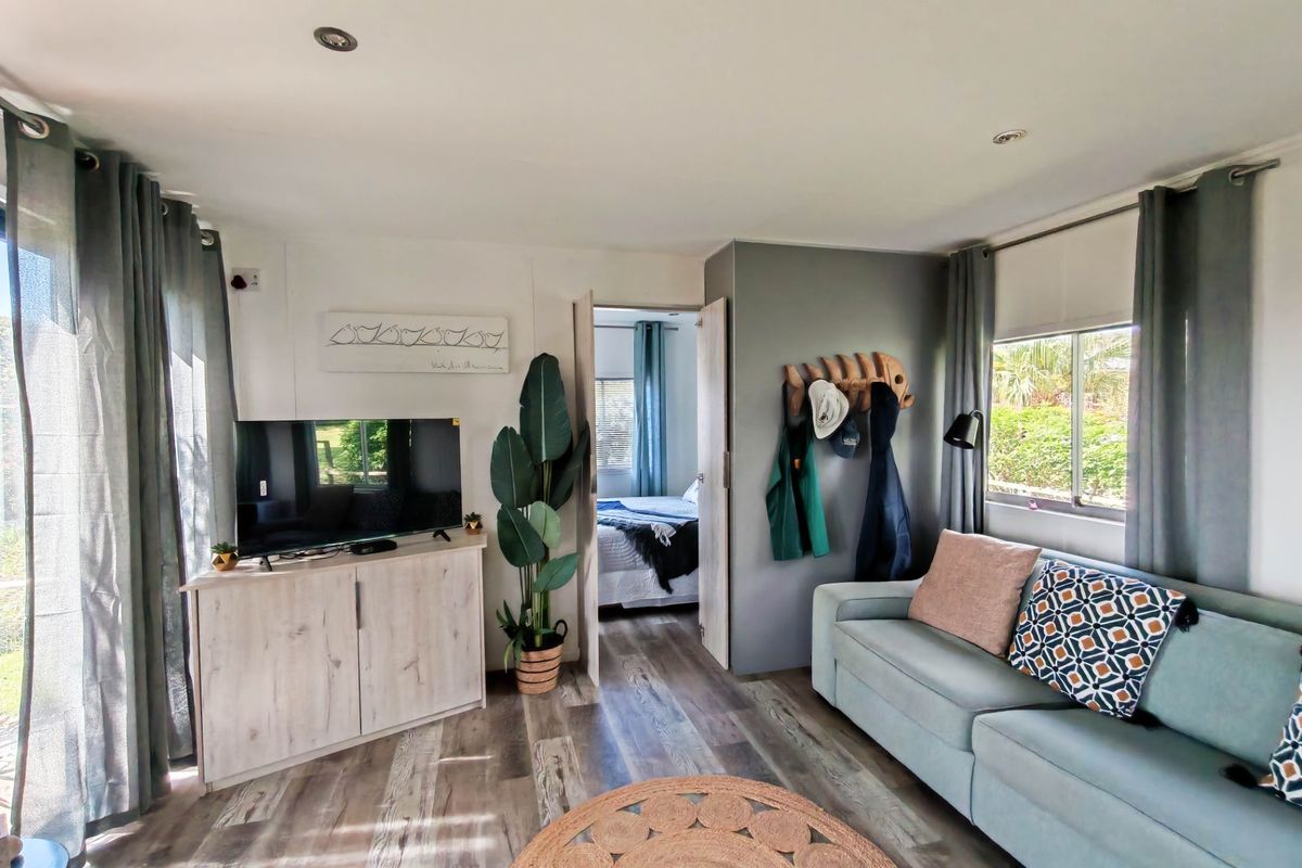 A bright living room featuring modern laminate flooring, recessed lighting, and large windows with blinds, providing a comfortable and well-lit living space.