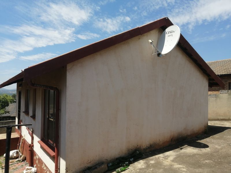 Side view of the property showing exterior wall, roofline, and satellite dish installation with visible signs of weathering and maintenance requirements.