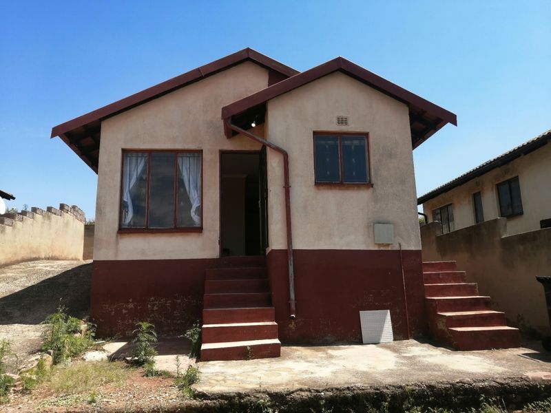 Front elevation of a detached house featuring a dual-staircase entrance, tiled roof, and weathered exterior wall finishes.