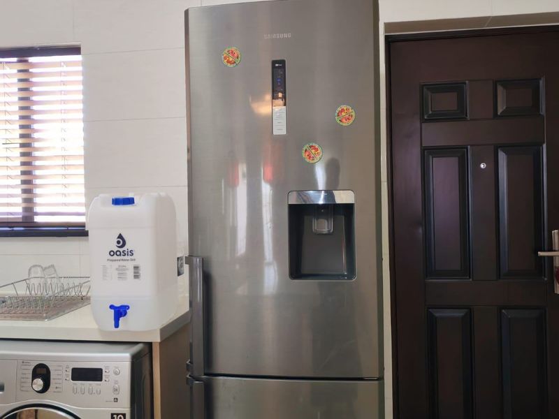 A functional kitchen area featuring tiled walls, a built-in washing machine, and a stainless steel refrigerator.