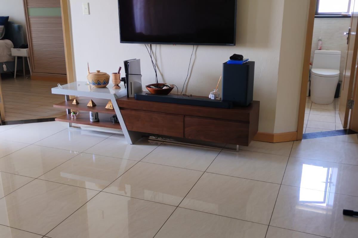 A living area featuring polished porcelain floor tiles, neutral wall finishes, and access to adjacent bedroom and bathroom spaces.