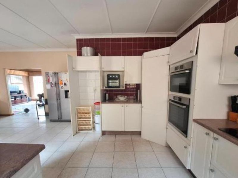 A functional kitchen featuring built-in double ovens, tiled splashbacks, and ample cabinetry, with an open-plan layout connecting to the adjacent living area.