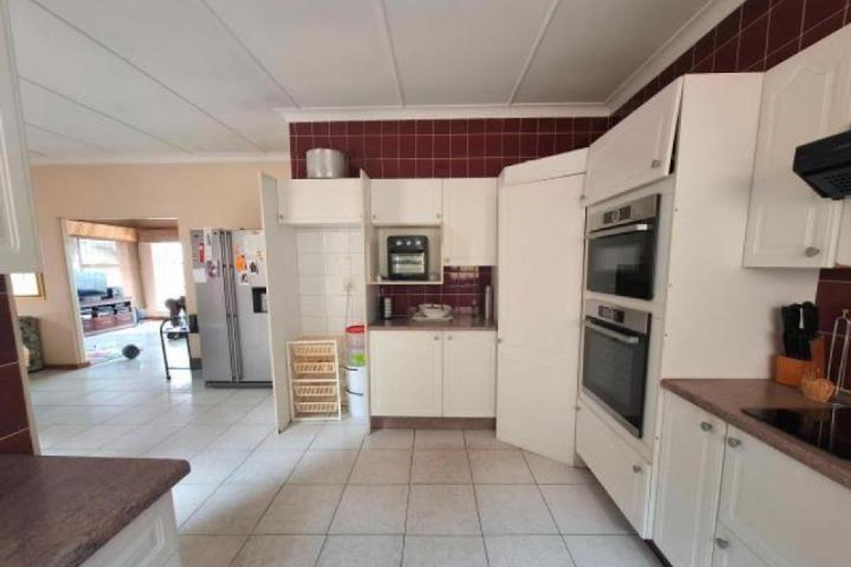 A functional kitchen featuring built-in double ovens, tiled splashbacks, and ample cabinetry, with an open-plan layout connecting to the adjacent living area.
