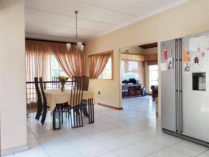 Open plan dining area featuring tiled flooring and coved ceilings, flowing into an adjacent living space.