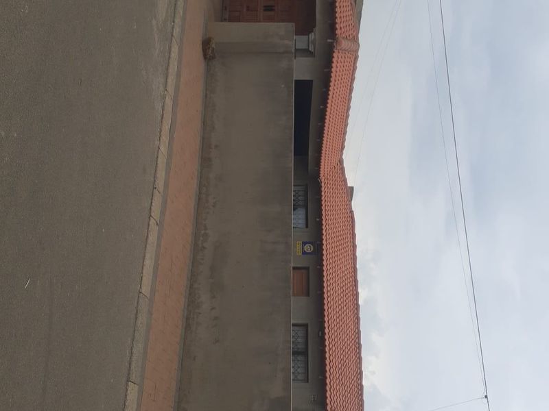 Front exterior view of the property featuring a terracotta tiled roof, boundary wall, and security features.