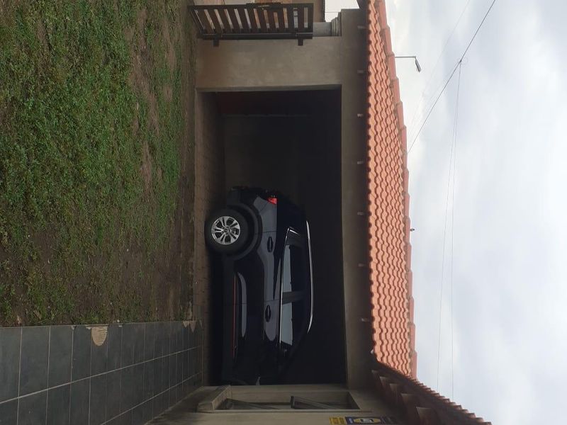 A view of the property garage with a tiled roof and adjacent tiled walkway area.