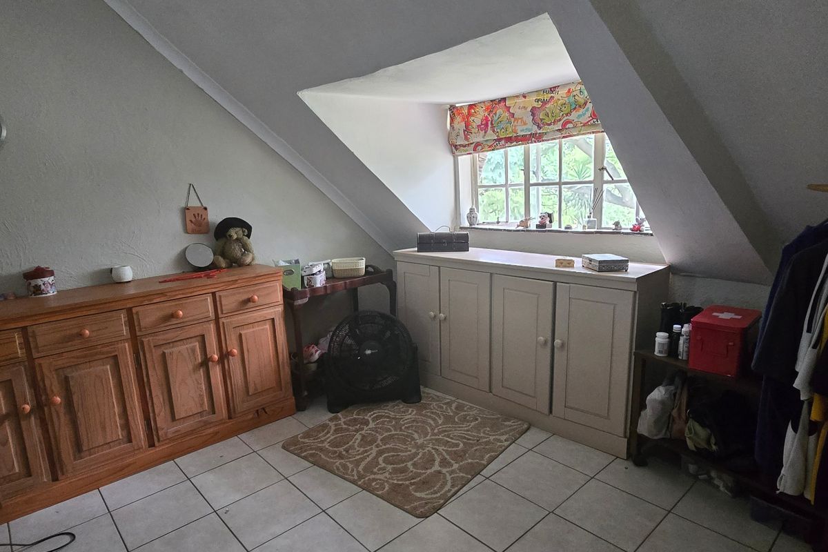 Attic-style bedroom featuring a dormer window, built-in storage cabinetry, and tiled flooring under a sloped ceiling.