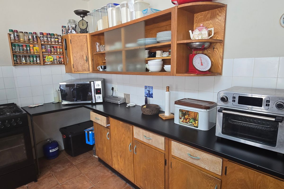A functional kitchen featuring wooden cabinetry, tiled backsplash, and a gas stove, offering a traditional farm-style aesthetic with ample counter space.