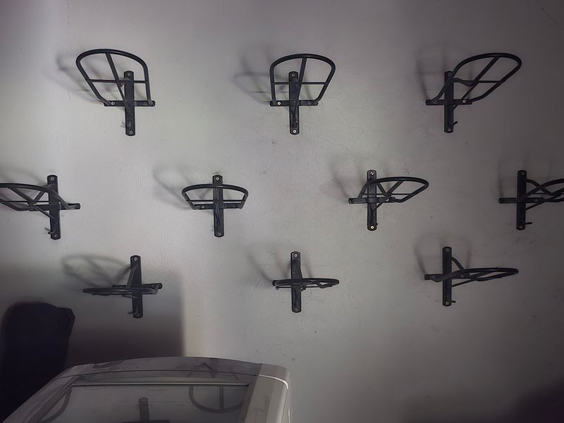 A utility space featuring multiple wall-mounted metal saddle racks, suitable for equestrian storage or farm equipment organization.