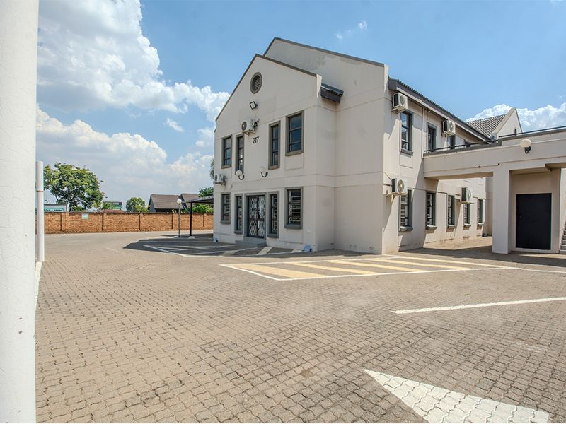 Commercial property exterior featuring a paved parking area, multi-level building facade with mounted air conditioning units, and a covered walkway entrance.