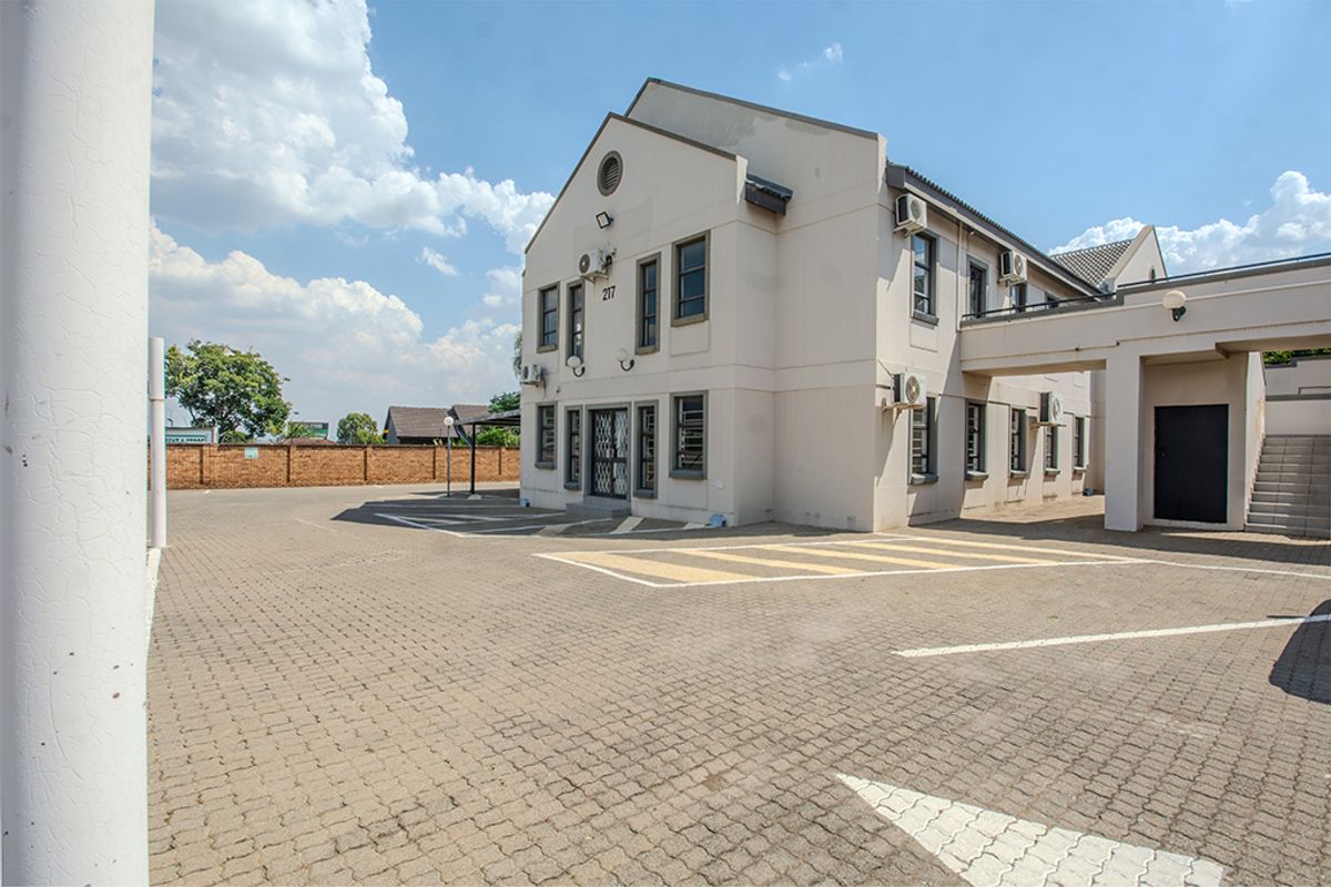 Commercial property exterior featuring a paved parking area, multi-level building facade with mounted air conditioning units, and a covered walkway entrance.