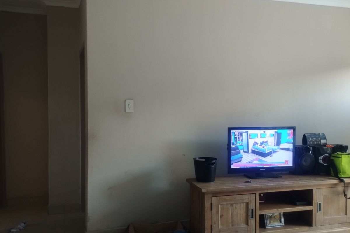 A living room area featuring neutral wall paint, standard electrical fixtures, and skirting boards, showing signs of wear on the wall surfaces.