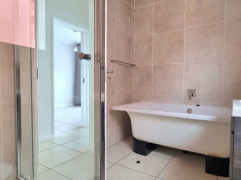 A modern bathroom featuring a freestanding bathtub, a separate glass-enclosed shower, and a vanity unit with neutral wall and floor tiling.