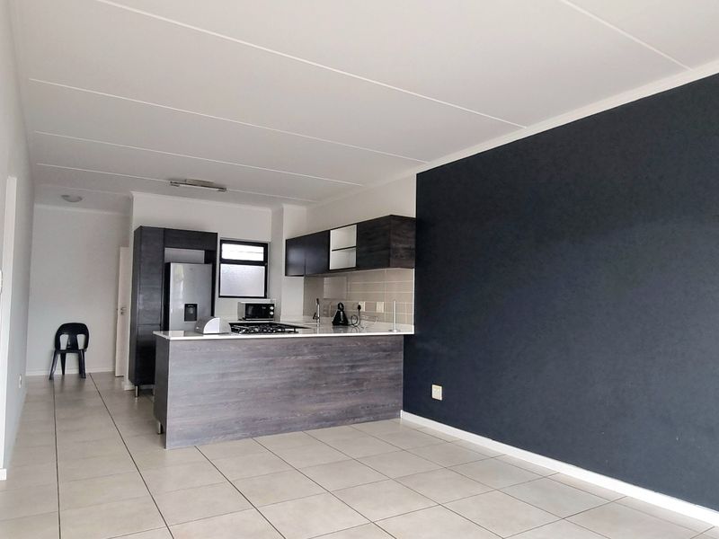 Open-plan living area featuring a modern kitchen with built-in cabinetry, gas hob, and tiled flooring throughout.