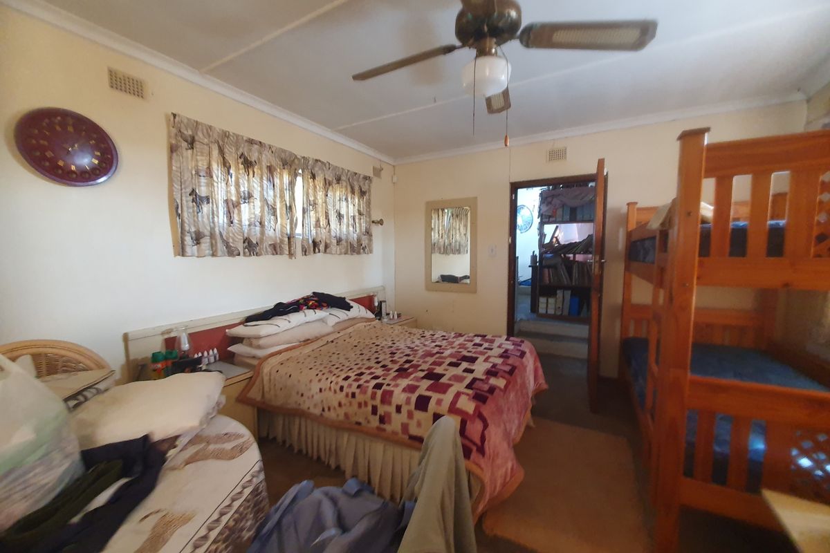 A bedroom featuring a ceiling fan and built-in headboard, providing functional space with access to an adjacent room.