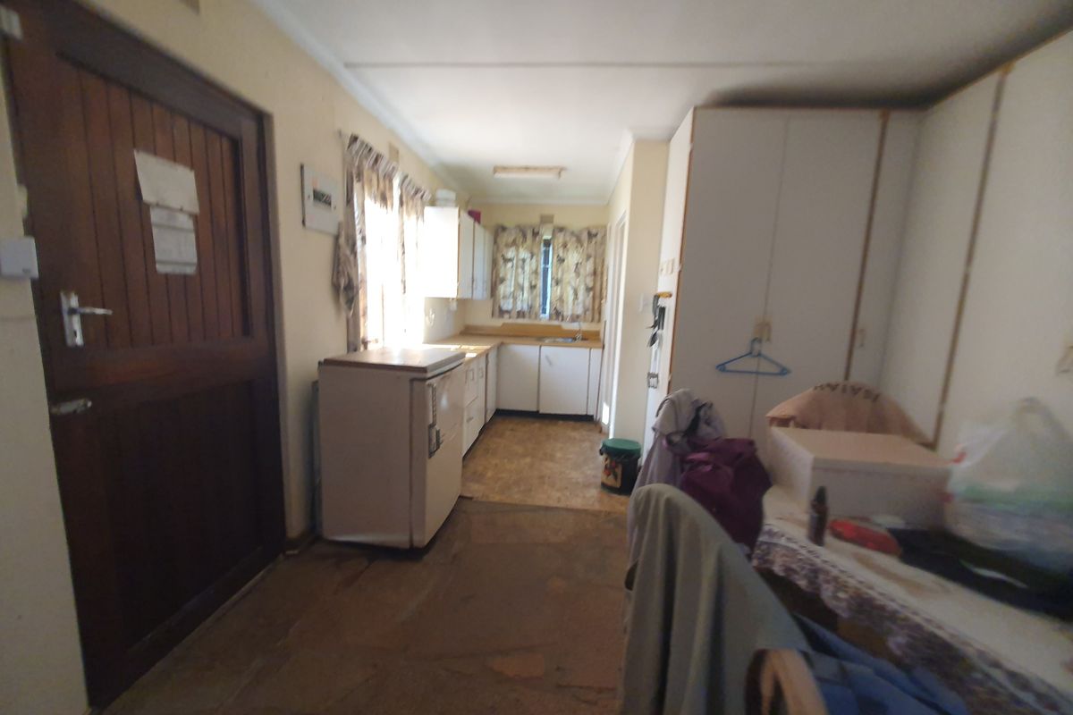 A dated kitchen area featuring built-in cabinetry and a sink, requiring modernization to improve functionality and aesthetic appeal.