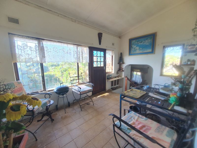 A sunlit enclosed patio area featuring tiled flooring, security bars on windows, and direct access to the exterior.