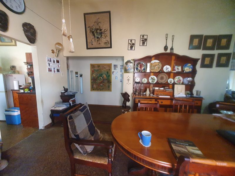 A dining area featuring an open-plan layout with an archway leading to the kitchen, showcasing traditional architectural elements and a functional floor plan.