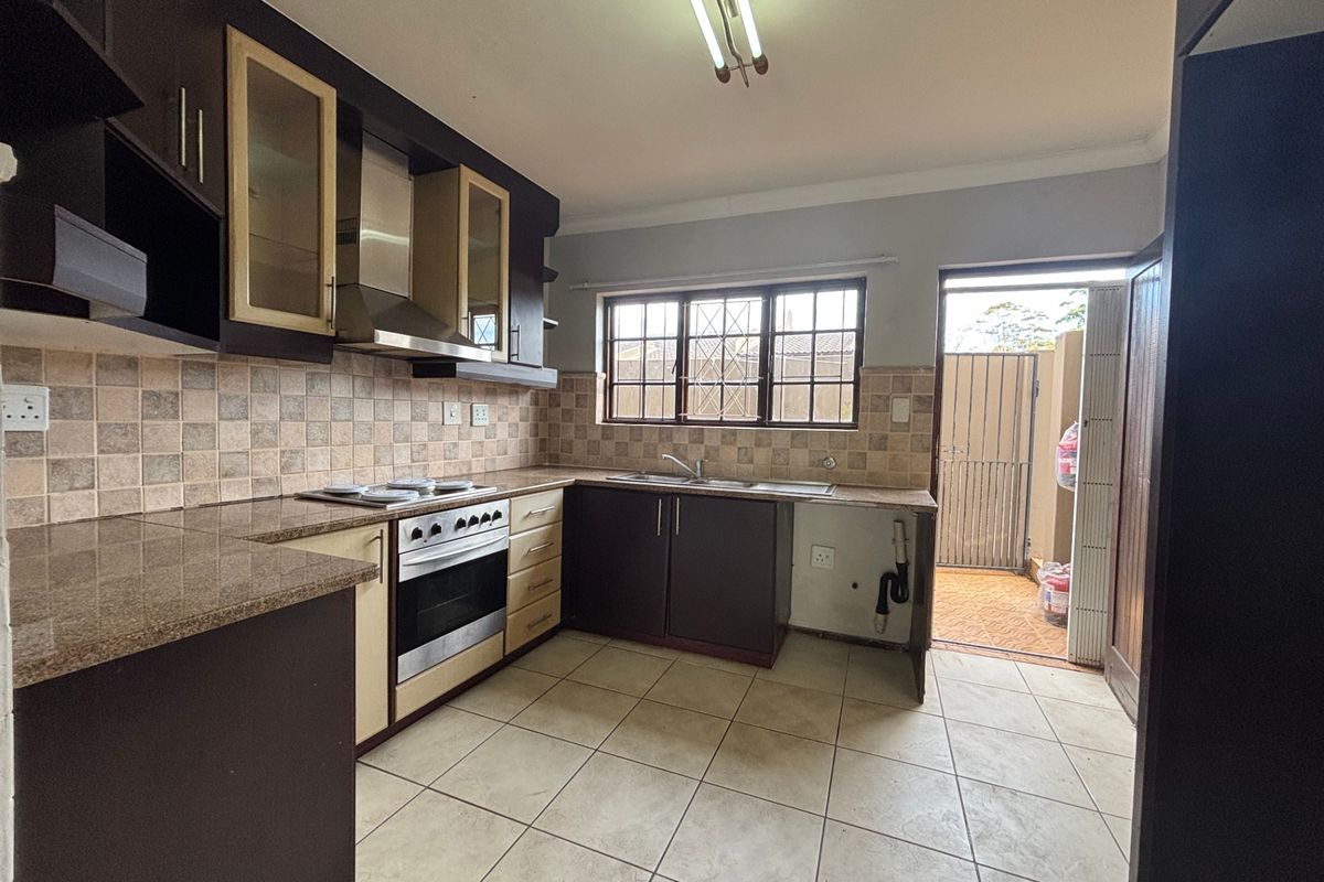 Functional kitchen featuring dark cabinetry, granite countertops, built-in oven with extractor, and direct access to an outdoor area.