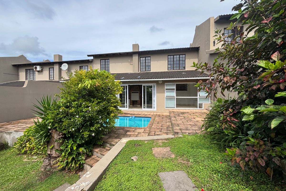 Rear view of the townhouse featuring a private swimming pool, paved patio area, and direct access through sliding glass doors.