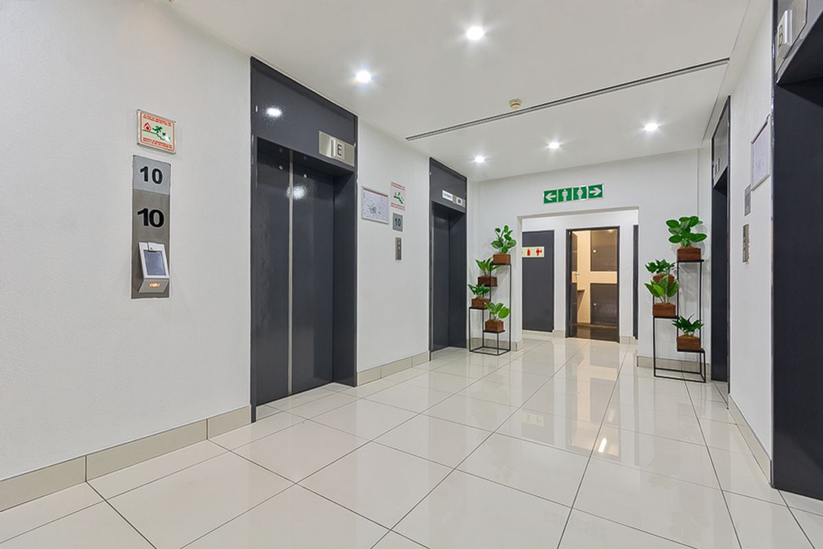 A clean, modern commercial elevator lobby featuring polished tile flooring, recessed lighting, and professional signage in a well-maintained office building.
