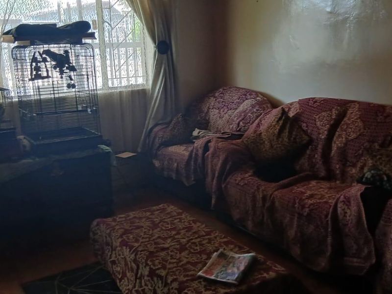 A living room featuring a large window with security bars, providing natural light to the space.