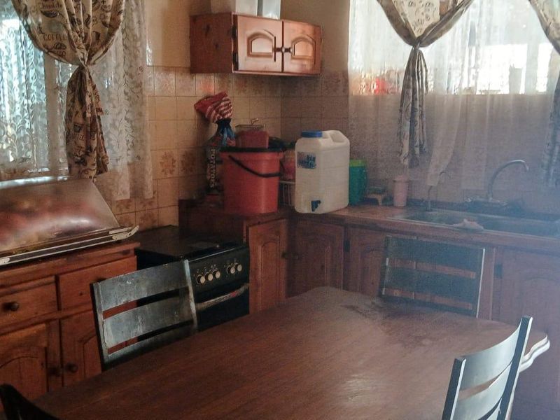 A dated kitchen featuring wooden cabinetry, a built-in stove, and a tiled backsplash, offering potential for modernization and renovation.