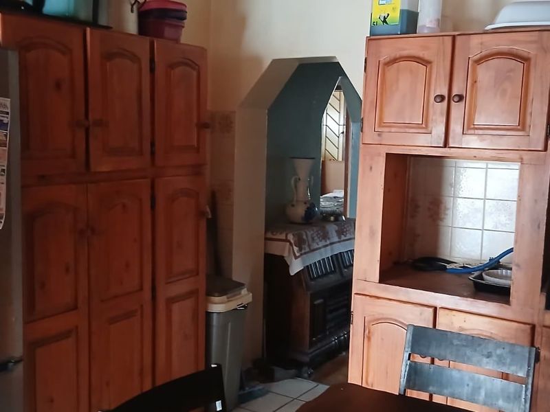 A dated kitchen featuring traditional wooden cabinetry, a built-in oven, and a gas hob, with an archway leading to an adjacent room.