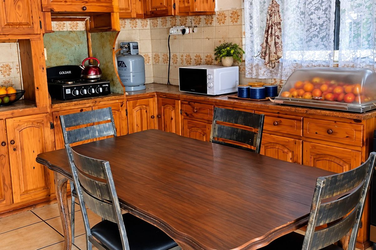 A traditional kitchen featuring extensive wooden cabinetry, tiled backsplash, and tiled flooring, offering a functional layout with built-in cooking appliances.