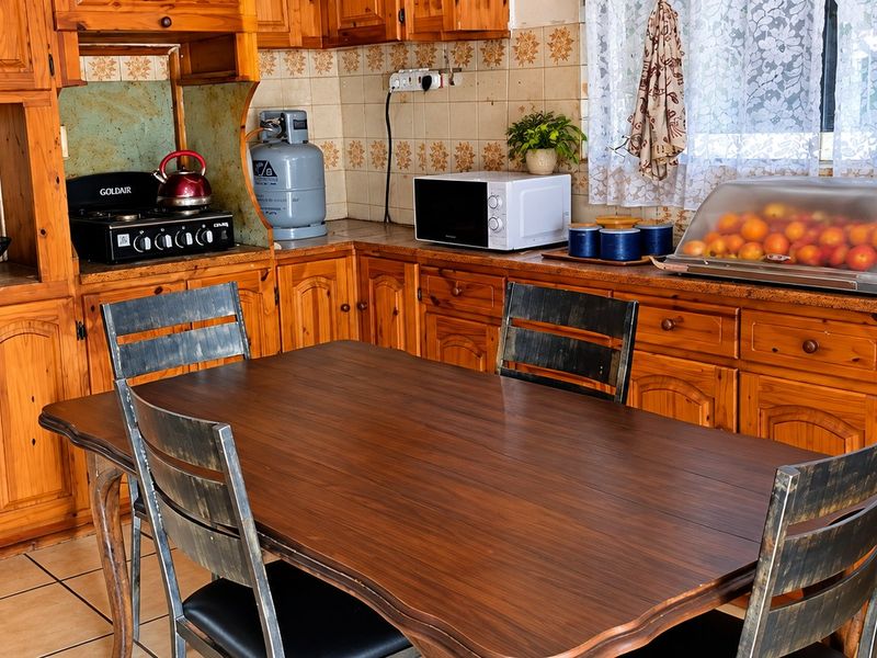 A traditional kitchen featuring extensive wooden cabinetry, tiled backsplash, and tiled flooring, offering a functional layout with built-in cooking appliances.