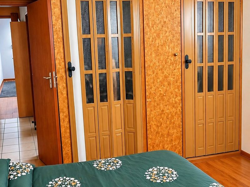Bedroom featuring extensive built-in cabinetry with wood-look finish, a ceiling fan, and timber ceiling paneling.