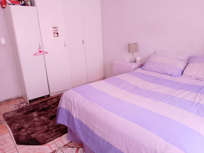 A bedroom featuring built-in white wardrobes and tiled flooring.