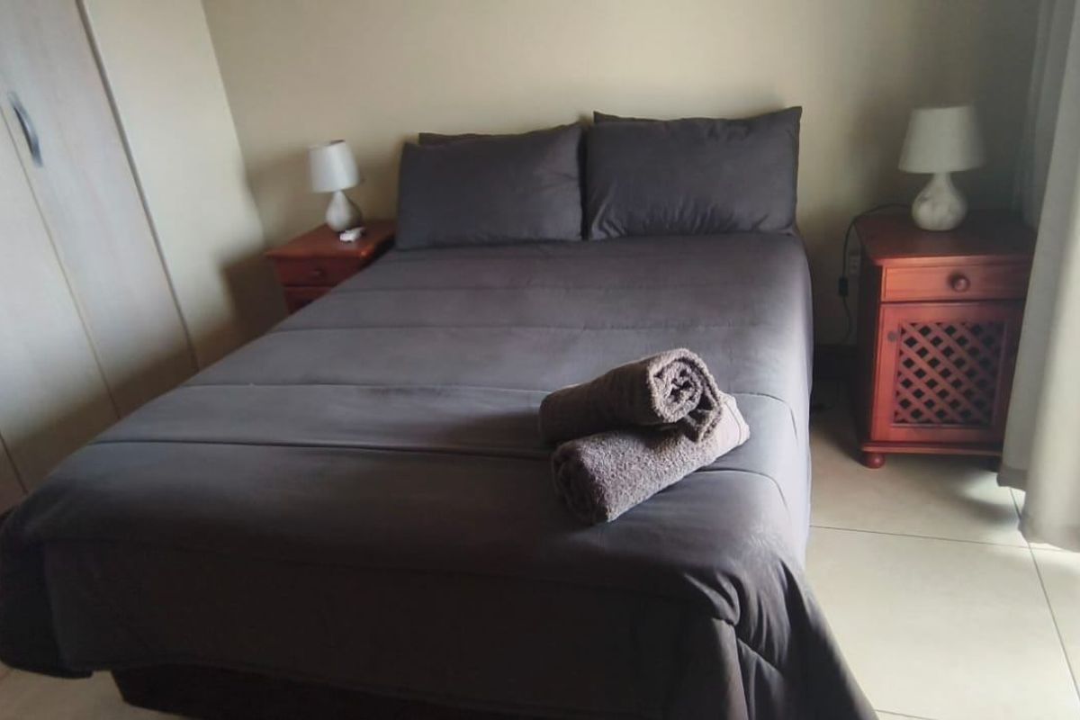 A bedroom featuring built-in cupboards, tiled flooring, and a sliding door providing access to an outdoor area.