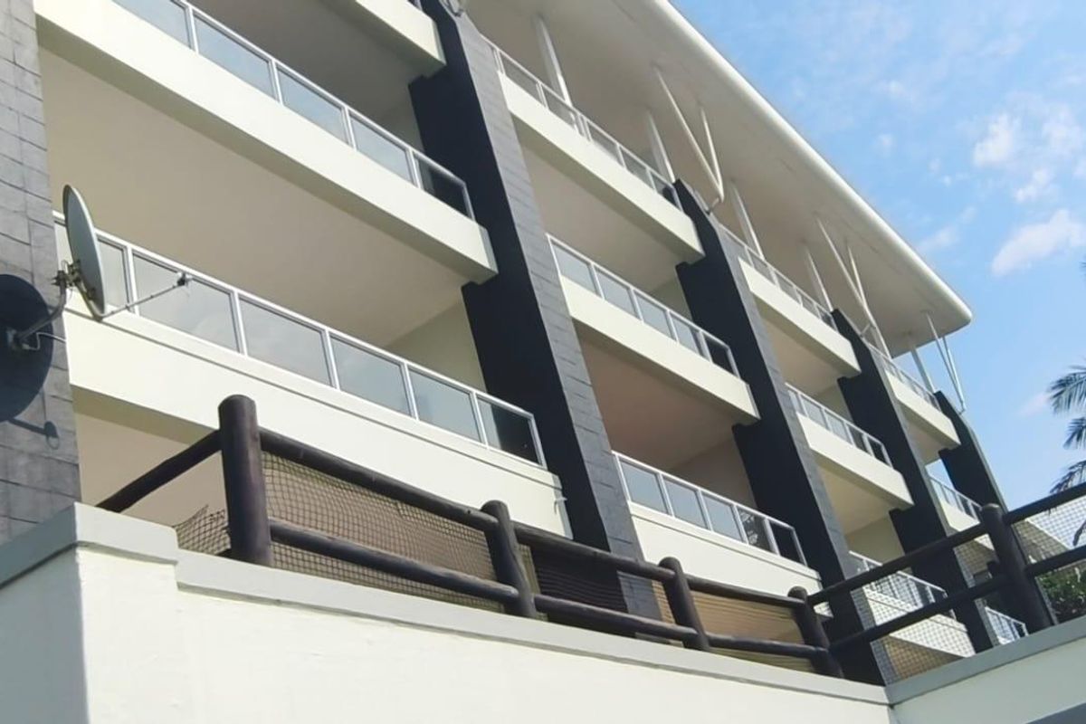 Low angle view of a modern apartment building facade featuring multiple levels of balconies with glass balustrades and dark structural accents.