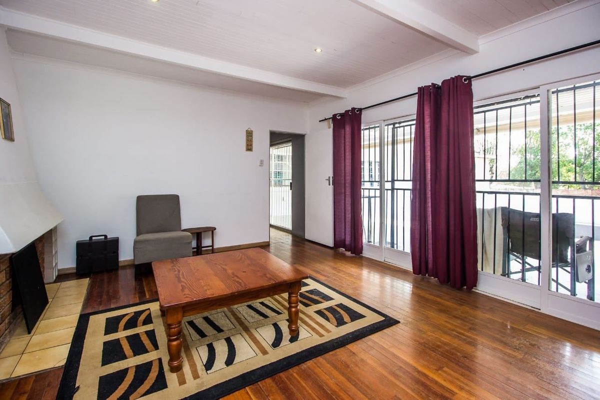 A living room featuring hardwood flooring, a brick fireplace, and sliding glass doors that provide access to the outdoor area.