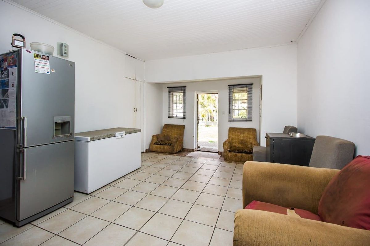 A functional kitchen area featuring tiled flooring, built-in storage, and direct access to the rear exterior, offering potential for modernization and layout optimization.