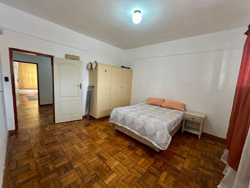 A bedroom featuring classic parquet flooring, a built-in wardrobe, and direct access to an adjoining hallway.