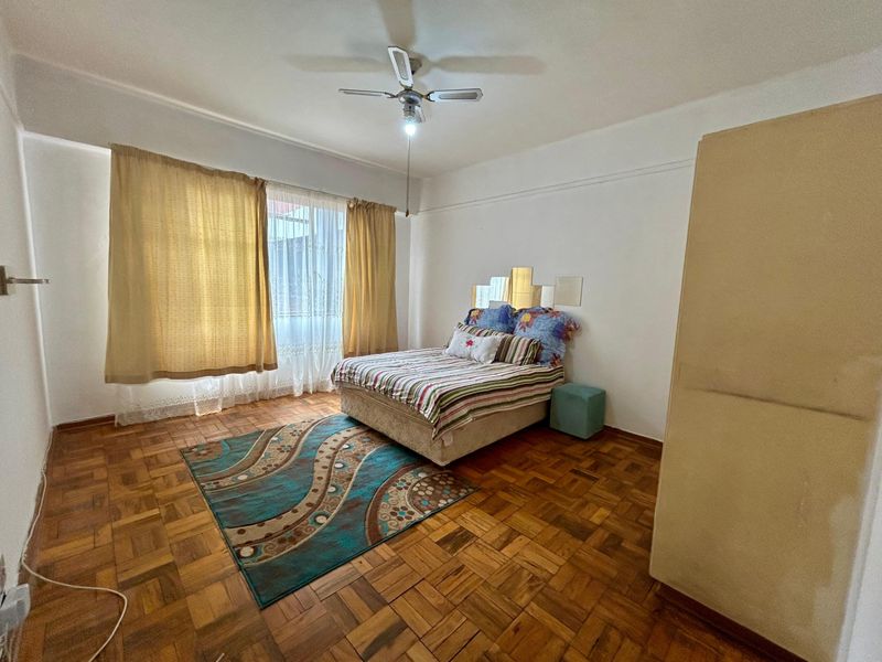A bedroom featuring classic parquet flooring and a ceiling fan, offering a neutral space ready for modern updates.