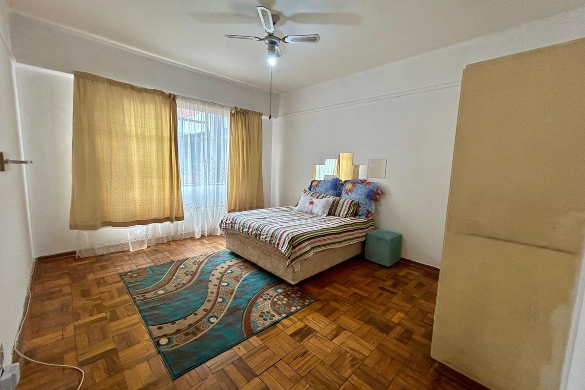 A bedroom featuring classic parquet flooring and a ceiling fan, offering a neutral space ready for modern updates.