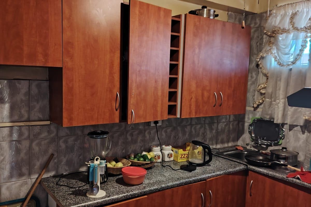 A functional kitchen featuring wood-tone laminate cabinetry, granite countertops, and tiled backsplash, currently showing signs of wear and dated finishes.