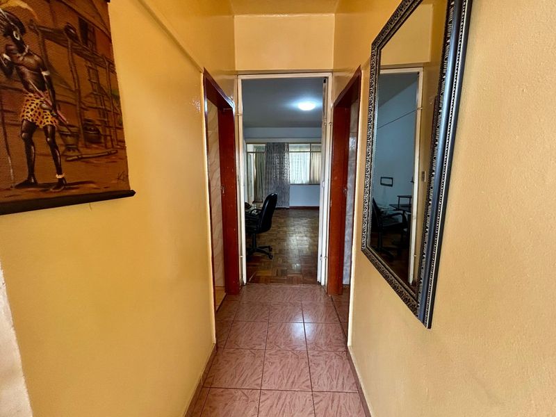 A functional hallway with tiled flooring connecting to an adjacent room, featuring neutral wall tones and clear access points.