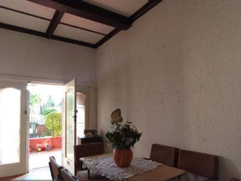 Living area featuring exposed timber ceiling beams, textured walls, and double glass doors providing access to the outdoor patio area.