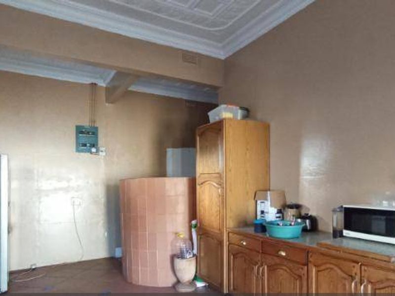 A dated kitchen featuring traditional wooden cabinetry, tiled surfaces, and ornate ceiling detailing, offering significant potential for a modern renovation.