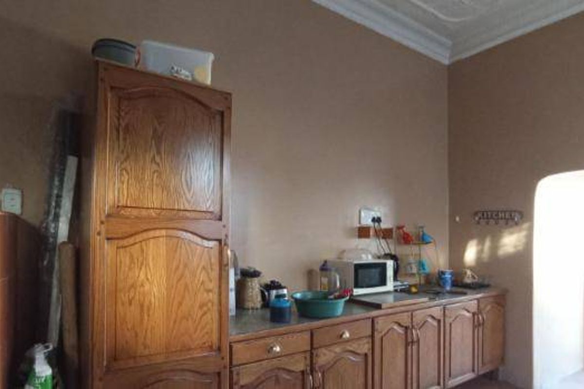 A dated kitchen featuring wooden cabinetry, a built-in microwave, and a sink, with potential for modernization and improved layout.