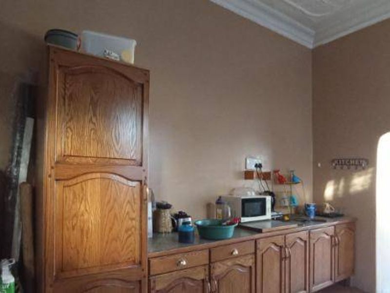 A dated kitchen featuring wooden cabinetry, a built-in microwave, and a sink, with potential for modernization and improved layout.