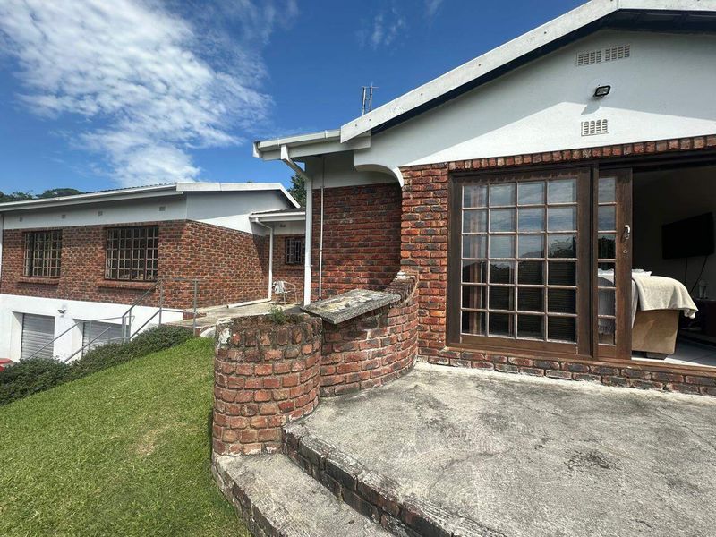 Rear exterior view featuring a brick facade, concrete patio area, and sliding glass doors providing access to the interior living space.