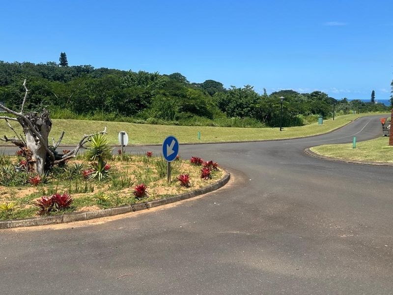 A view of the paved residential street and landscaped verge within the estate, showing well-maintained road infrastructure and surrounding greenery.