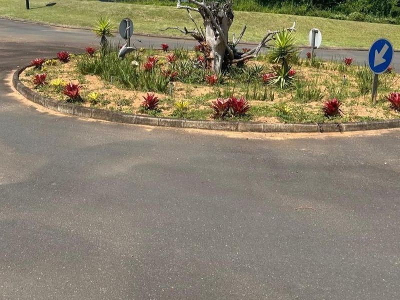 A view of a paved roundabout featuring landscaped garden beds and traffic signage within the residential estate.