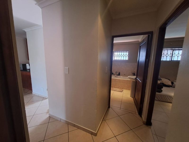 A view from the hallway looking into a bathroom and bedroom, featuring tiled flooring and standard interior finishes throughout the apartment.