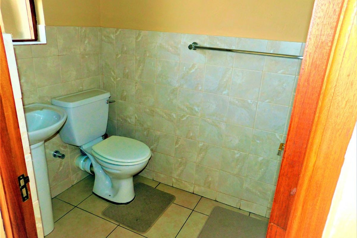 A functional bathroom featuring a pedestal basin, standard toilet, and tiled walls with a mounted towel rail.